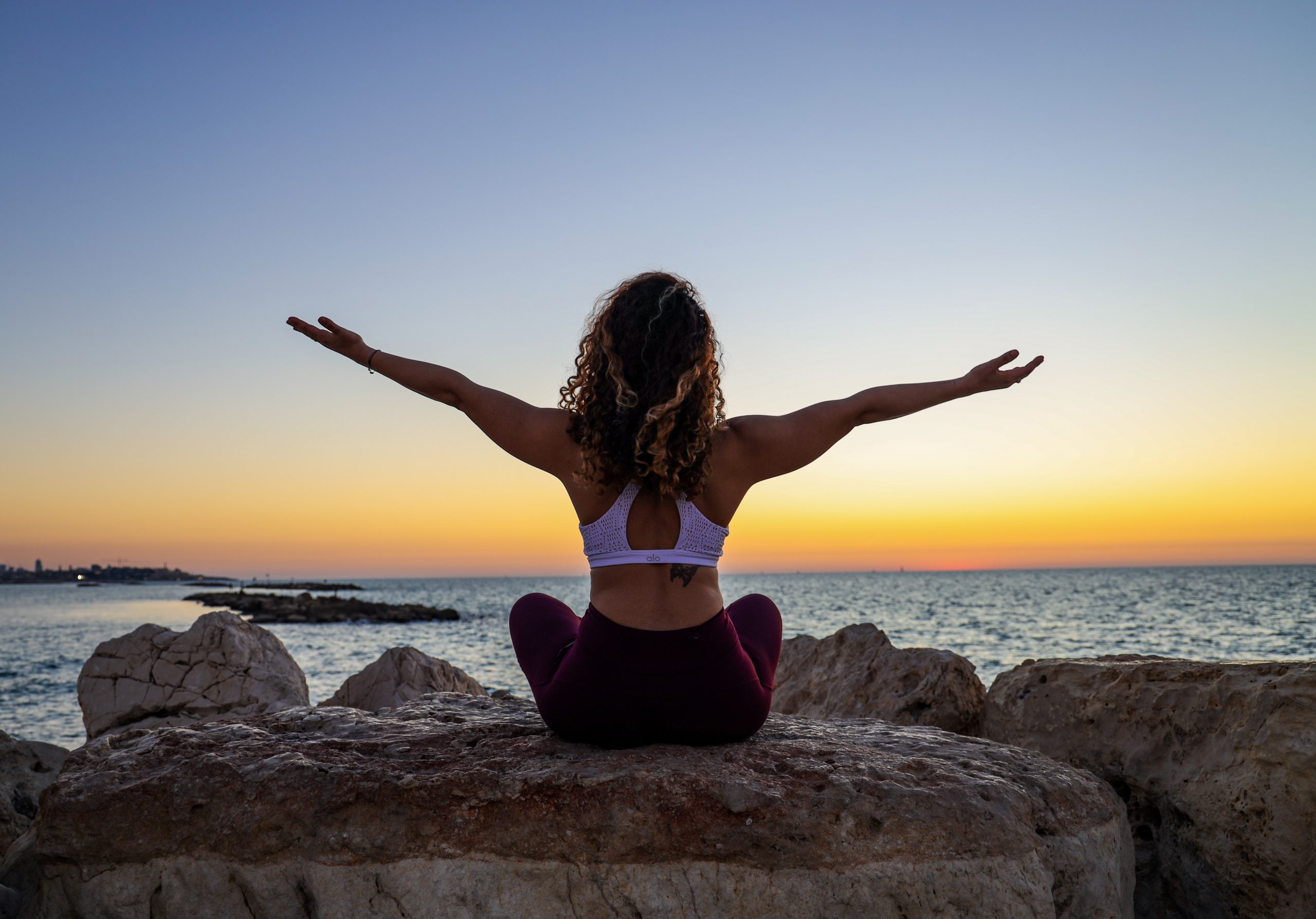 a woman/girl doing outdoor yoga exercise on the rocks